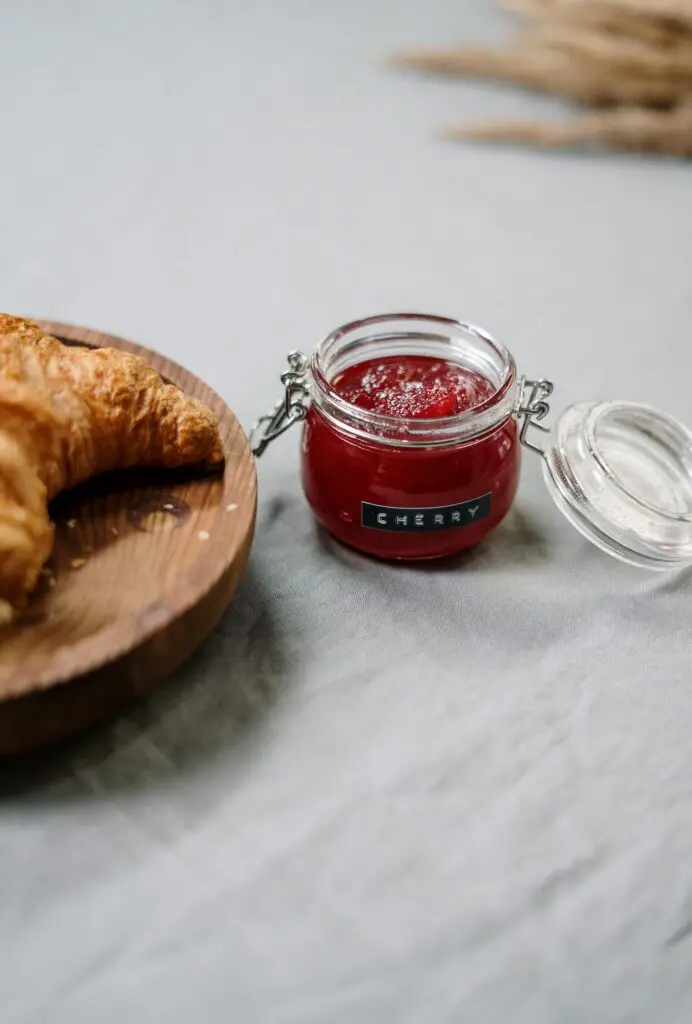 jam or jelly in a pot next to a croissant