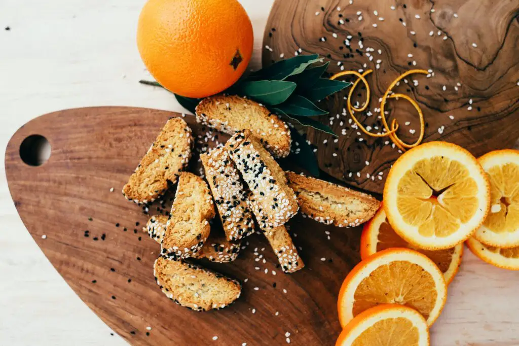 biscotti with sesame seeds and orange slices on wooden tray